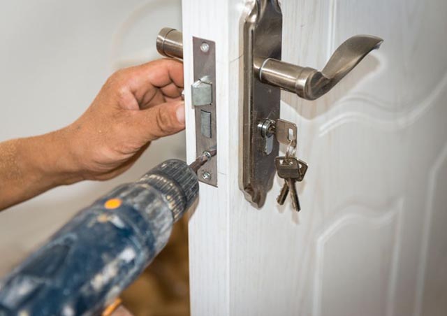 person-using-a-drill-to-secure-a-doors-locking-system person-using-a-drill-to-secure-a-doors-locking-system